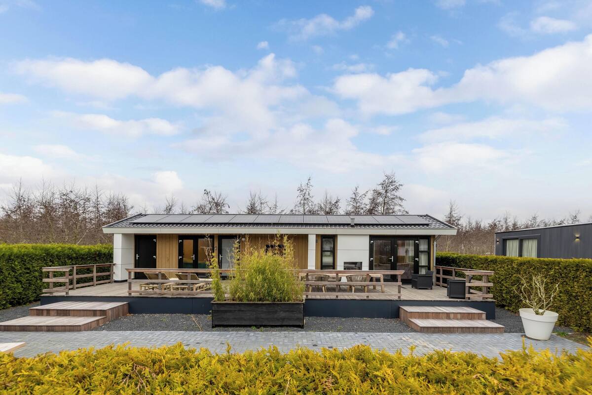 A modern building with outdoor seating, a garden, and a clear sky.