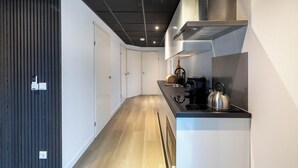 A modern kitchen with a stove, kettle, and cabinets. - Vakantiepark In Style (Menaldum)