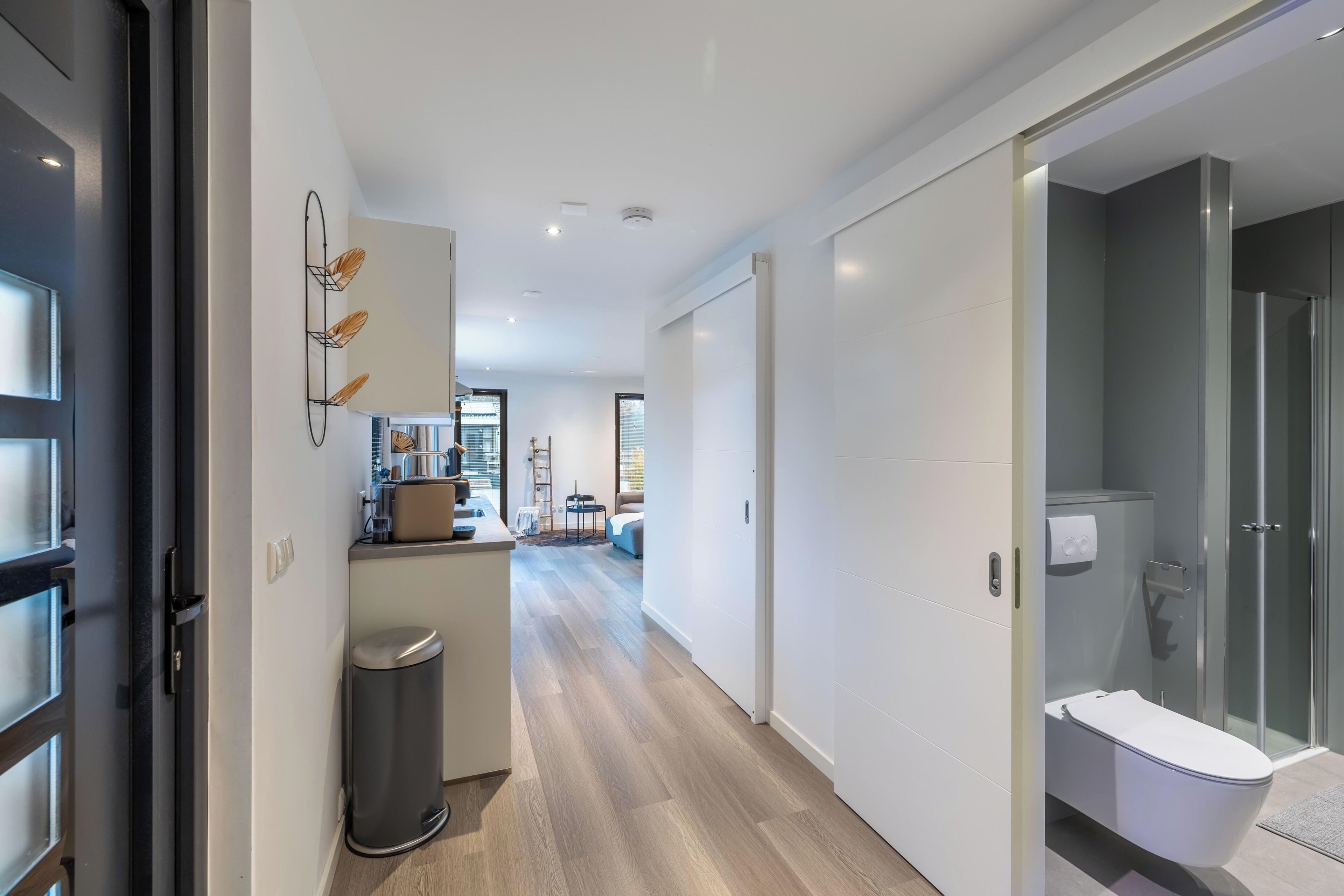 A modern interior with a kitchen, dining area, and a bathroom with a glass shower.
