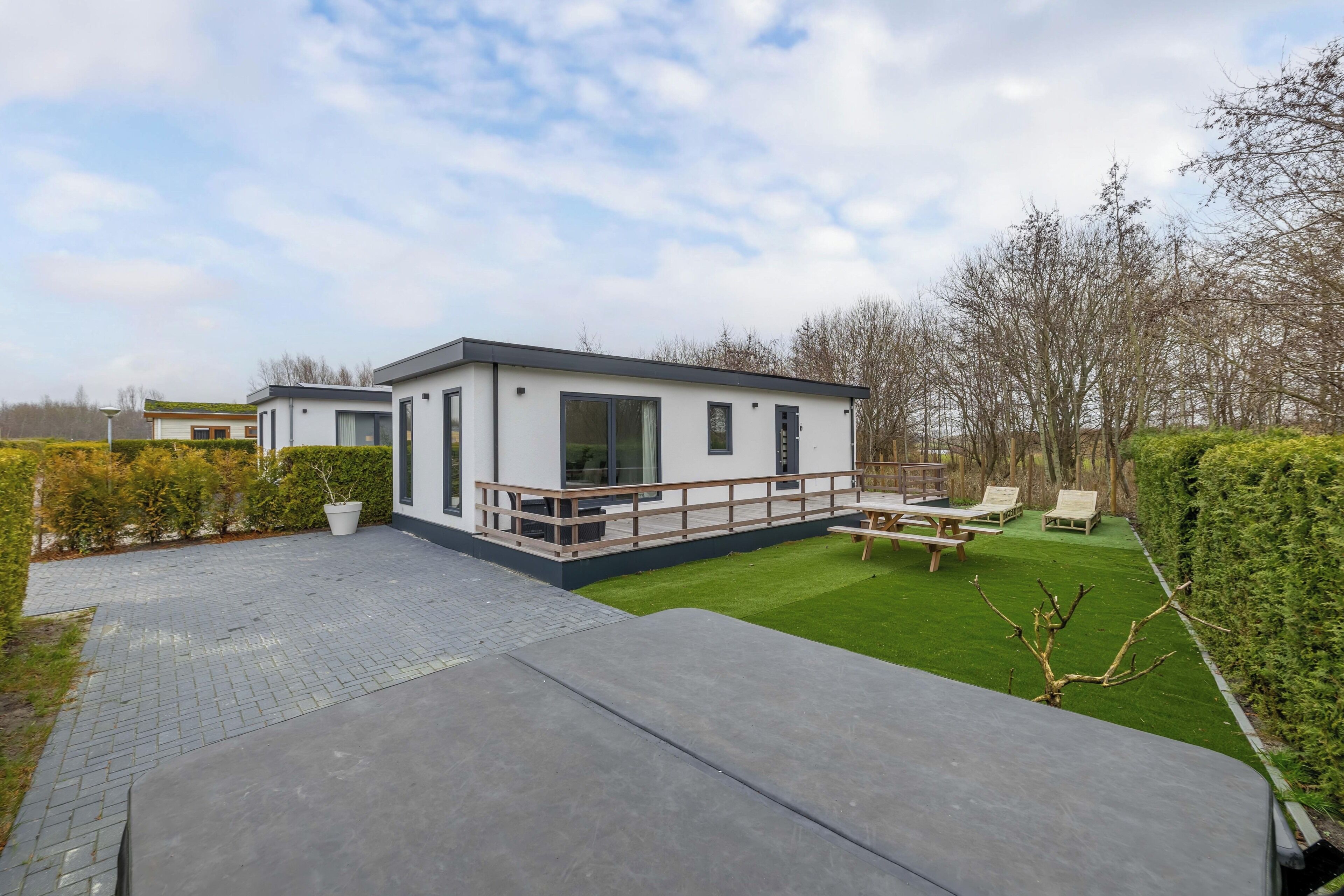A modern house with a patio, a lawn, and a wooden deck.