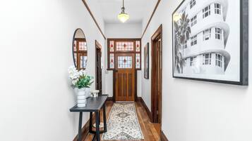 A hallway with a wooden door, a black table with a vase, and a patterned rug.