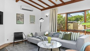 Un salón moderno con un sofá, una silla, una mesita de centro y un ventanal con vistas a zonas verdes.
