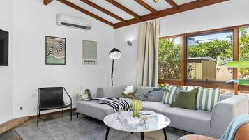 A modern living room with a sofa, a chair, a coffee table, and a large window with a view of greenery.