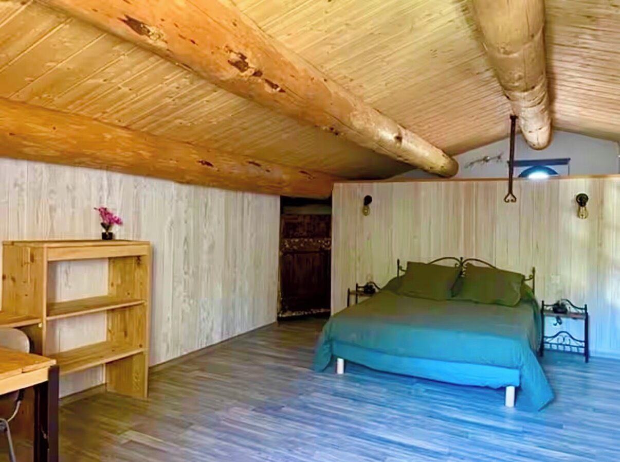 Een kamer met een bed, een houten bureau en een plank.
