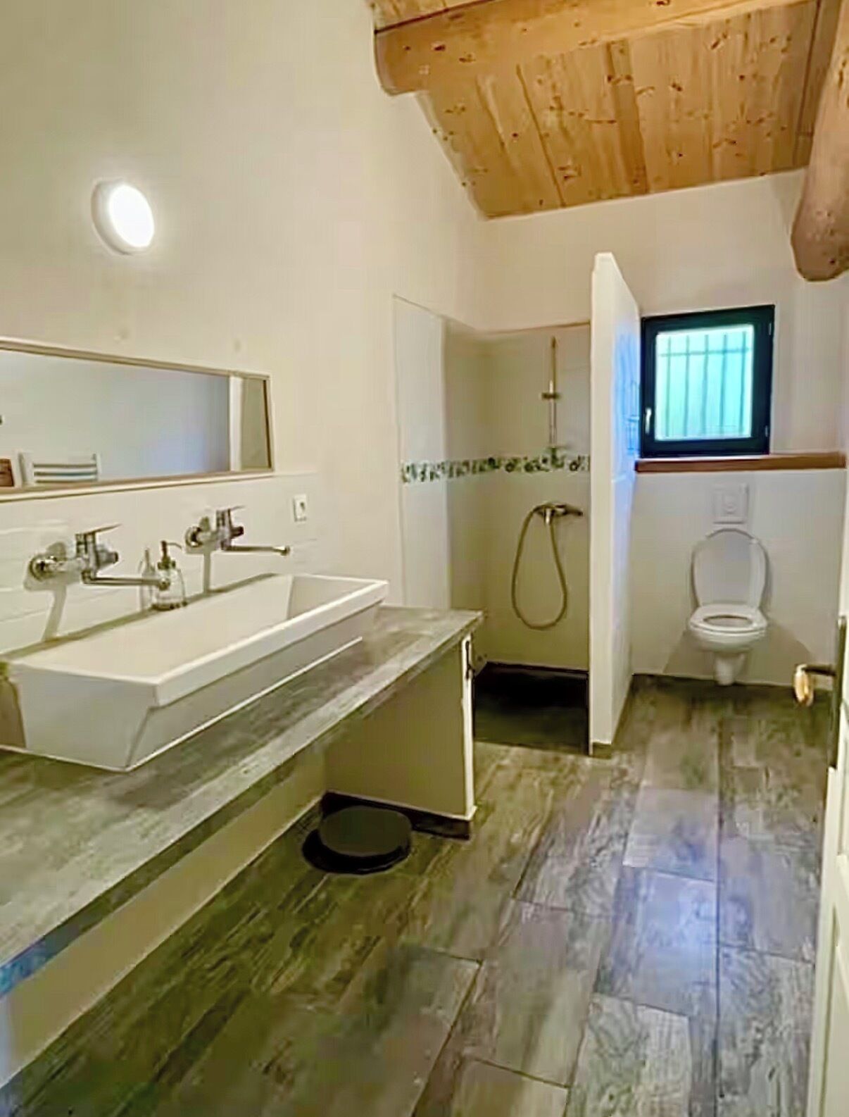 Un baño con lavamanos, espejo, ducha e inodoro.