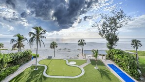 A coastal view with a beach, palm trees, and a well-maintained lawn. - Gulf-View Beachfront Condo – Unit 203 – Longboat Key (Longboat Key)