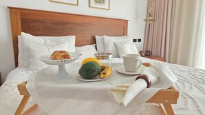 A neatly made bed with a tray of food, a cup, and a small table. - Anguila 102 – Stylish Beachfront Apartment Aqua Esmeralda, Dominicus (Dominicus)
