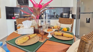 A modern kitchen with white cabinets, a stainless steel refrigerator, and a dining table set with a vase of flowers, plates, and napkins. - Anguila 102 – Stylish Beachfront Apartment Aqua Esmeralda, Dominicus (Dominicus)
