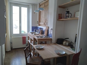 A kitchen with a wooden table, chairs, a window, and a radiator. - Downtown apartment with garden (Avallon)