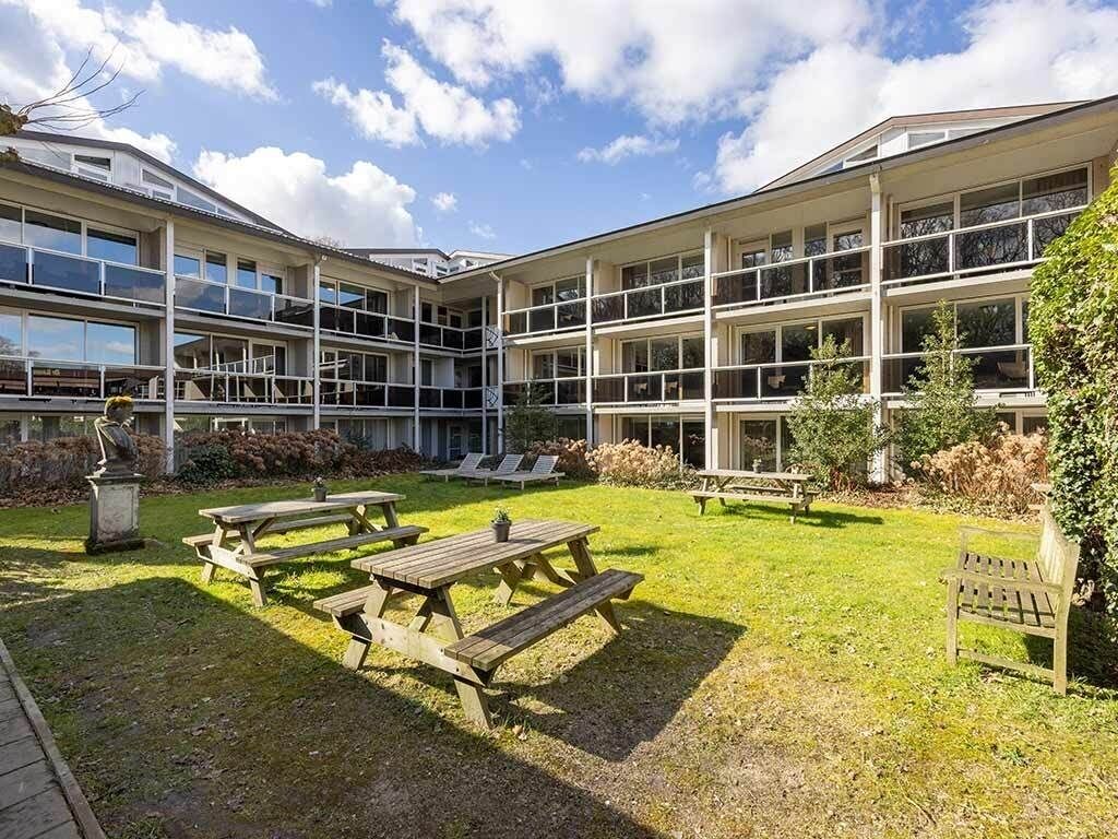 Un edificio de varios pisos, con mesas al aire libre y un patio cubierto de césped.