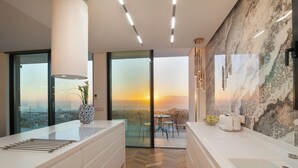 A modern kitchen with a large island, a view of the sunset, and a dining area with chairs. - Lux 250m NEW Villa E with heated pool, ocean view (Costa Adeje)