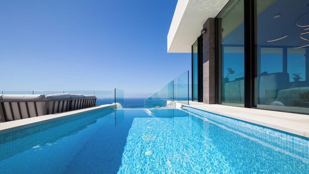 A modern infinity pool with clear blue water, a glass balustrade, and a view of the ocean. - Lux 250m NEW Villa E with heated pool, ocean view (Costa Adeje)