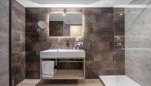 Un bany modern amb un mirall gran, un lavabo i una zona de dutxa.