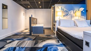 Une chambre d’hôtel avec un lit, une salle de bain avec un lavabo et un mur sur lequel est affiché un panneau indiquant : « ÉQUILIBRE VIE PROFESSIONNELLE ».