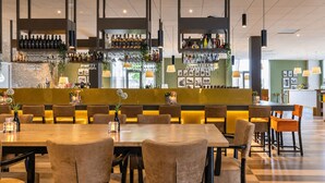 Un restaurant doté d’un bar, de plusieurs espaces pour s’asseoir et d’un sol à carreaux.