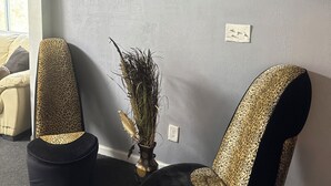 Et værelse med to lædersæder med leopardmønster, et indrammet billede af en leopard og dekorative væg spejle.