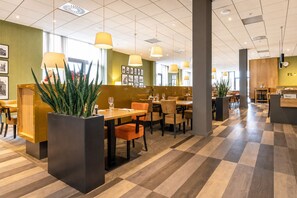 Ein modernes Restaurant mit Schachbrettfußboden, Holztischen und orangefarbenen Stühlen.