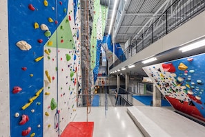 An indoor climbing facility with multiple climbing walls, a red padded area, and a mezzanine level with a railing. - 2 Tranquil Rooms with Spa & Fitness Center – Ideal for a Relaxing Trip (Sittard)
