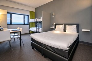 Ein modernes Hotelzimmer mit einem gro ßen Bett, einem Schreibtisch und Etagenbetten.