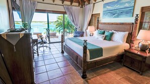 Une chambre d’hôtel avec un grand lit, un bureau et une vue sur l’océan.