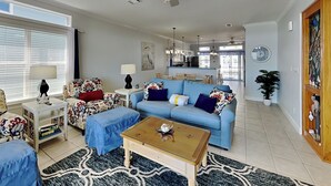 A living room with a blue sofa, a coffee table, a patterned armchair, a side table with a lamp, and a ceiling fan. - The Pearl At Oyster Lake | Chic Coastal Home, 0.4mi to Beach Access + Bikes (Santa Rosa  Beach)