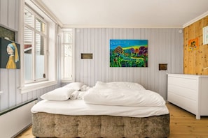 Un dormitorio con cama, ventana, cuadro y cómoda.