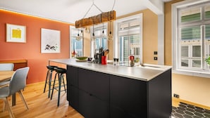 Una cocina moderna con una isla central, taburetes de bar y un comedor con mesa y sillas.