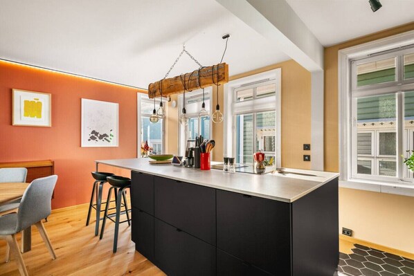 Una cocina moderna con una isla central, taburetes de bar y un comedor con mesa y sillas.