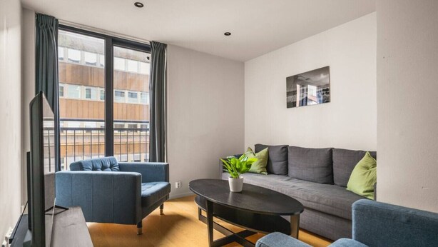 Una sala de estar moderna con un sofá, dos sillones, una mesita de centro y una planta en maceta.