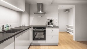 Una cocina moderna con encimera negra, electrodomésticos de acero inoxidable y horno integrado.