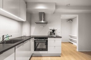 Una cocina moderna con encimera negra, electrodomésticos de acero inoxidable y horno integrado.