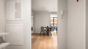 Un interior moderno con comedor, paredes blancas y suelo de madera.