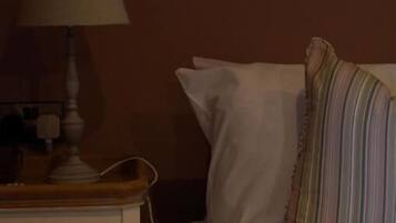 A hotel room with a bed, a nightstand with a lamp, and a striped pillow.
