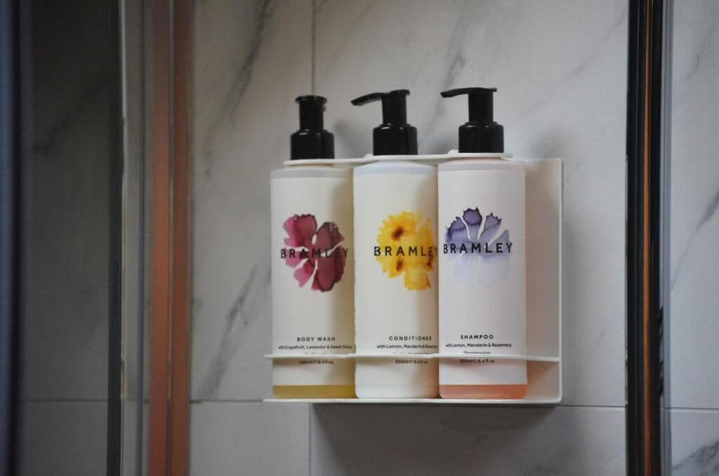 Trois produits de la gamme Brambley pour le soin du corps, présentés sur une étagère.
