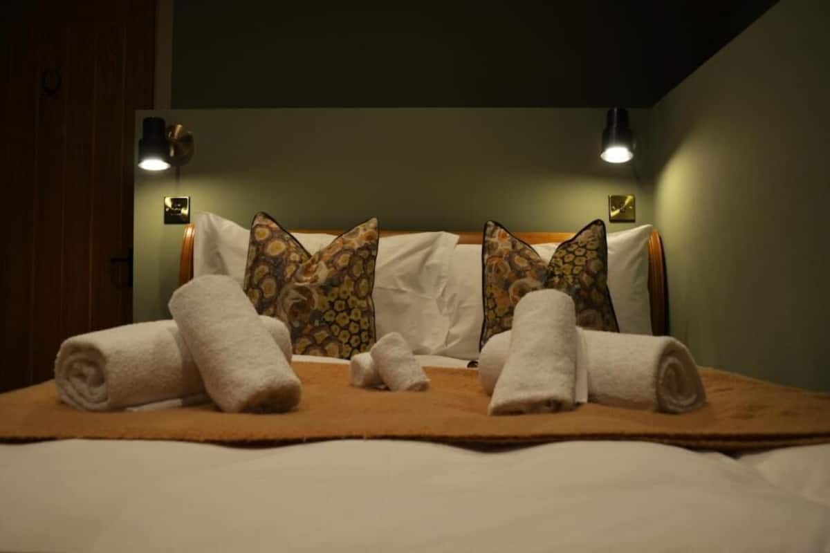 A neatly made bed with patterned pillows, a rolled towel, and a blanket.