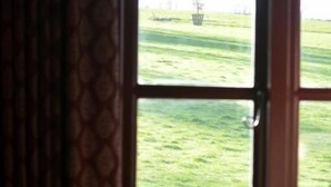 A room with a large window, a patterned curtain, and a chair.