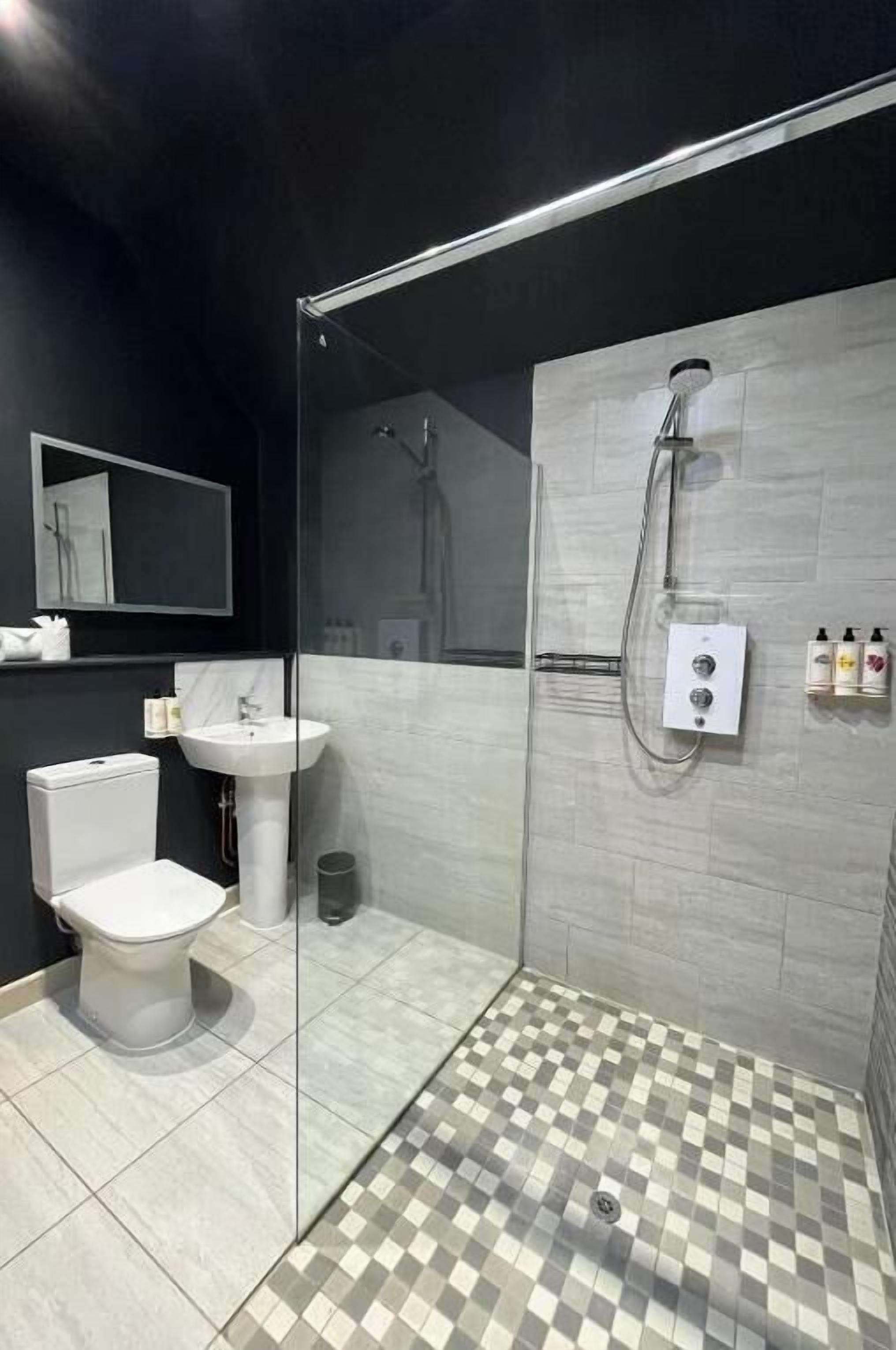 A modern bathroom with a glass-enclosed shower, a toilet, and a sink.