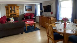 A living room with a sofa, armchair, dining table, and a TV. - BergZeit Karles | Winterberg—Your Favorite Spot on the Rothaarsteig•Ski•Hiking•Bike Park (Winterberg)