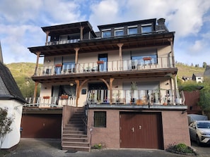 A multi-story building with a staircase leading to a garage, balconies with railings, and potted plants. - Apartment 'Wohnung' with Shared Garden, Balcony and Wi-Fi (Klotten)