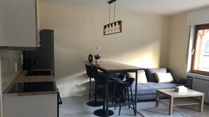 A modern kitchen with a dining area, a sofa, and a window.