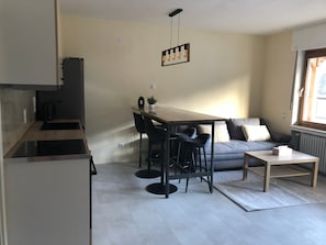 A modern kitchen with a dining area, a sofa, and a window. - Apartment 'Wohnung' with Shared Garden, Balcony and Wi-Fi (Klotten)
