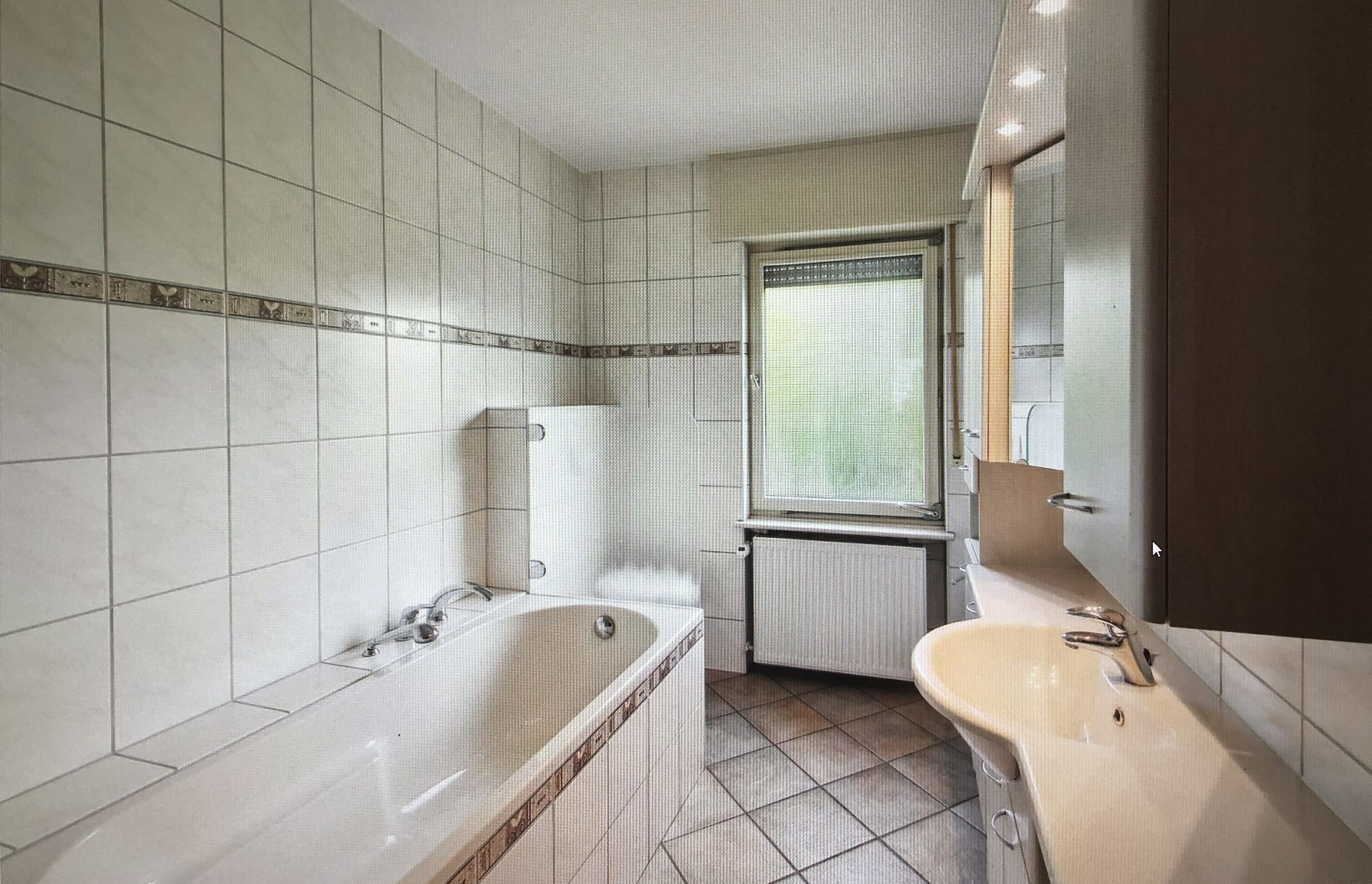 A bathroom with a bathtub, toilet, sink, and a window with a view.