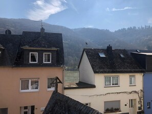 A residential building with a sloped roof, a chimney, and a window with a curtain. - Room 'Zimmer 2 1og' with Shared Garden, Balcony and Wi-Fi (Klotten)