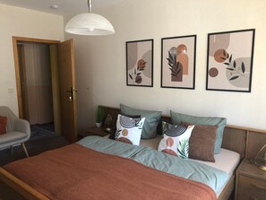 A bedroom with a bed, pillows, a nightstand, a lamp, and wall art. - Room 'Zimmer 2 1og' with Shared Garden, Balcony and Wi-Fi (Klotten)