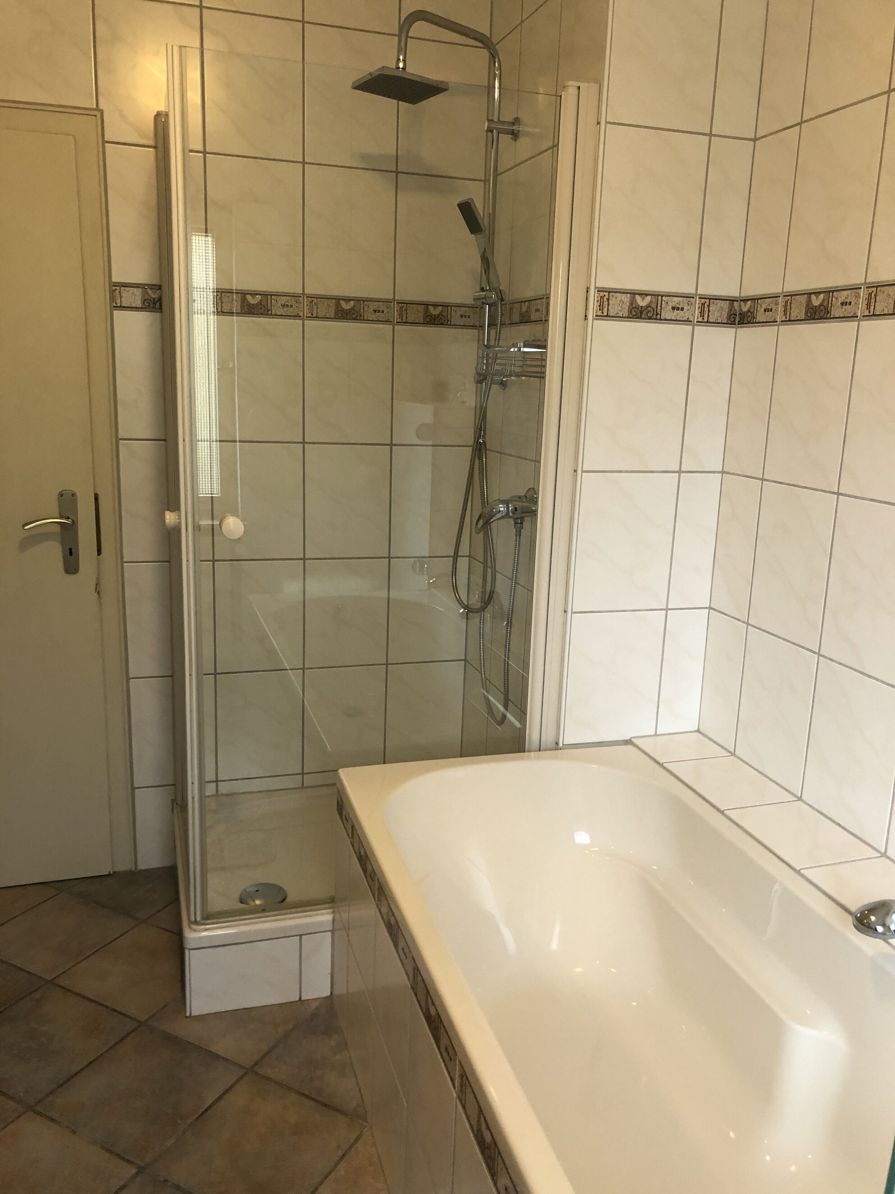 Ein Badezimmer mit einer Duschkabine, einer Badewanne und gefliesten Wänden.