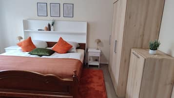 Ein Schlafzimmer mit einem Holzbett, einem weißen Nachttisch, einem Holzschrank und drei gerahmten Wandbildern.