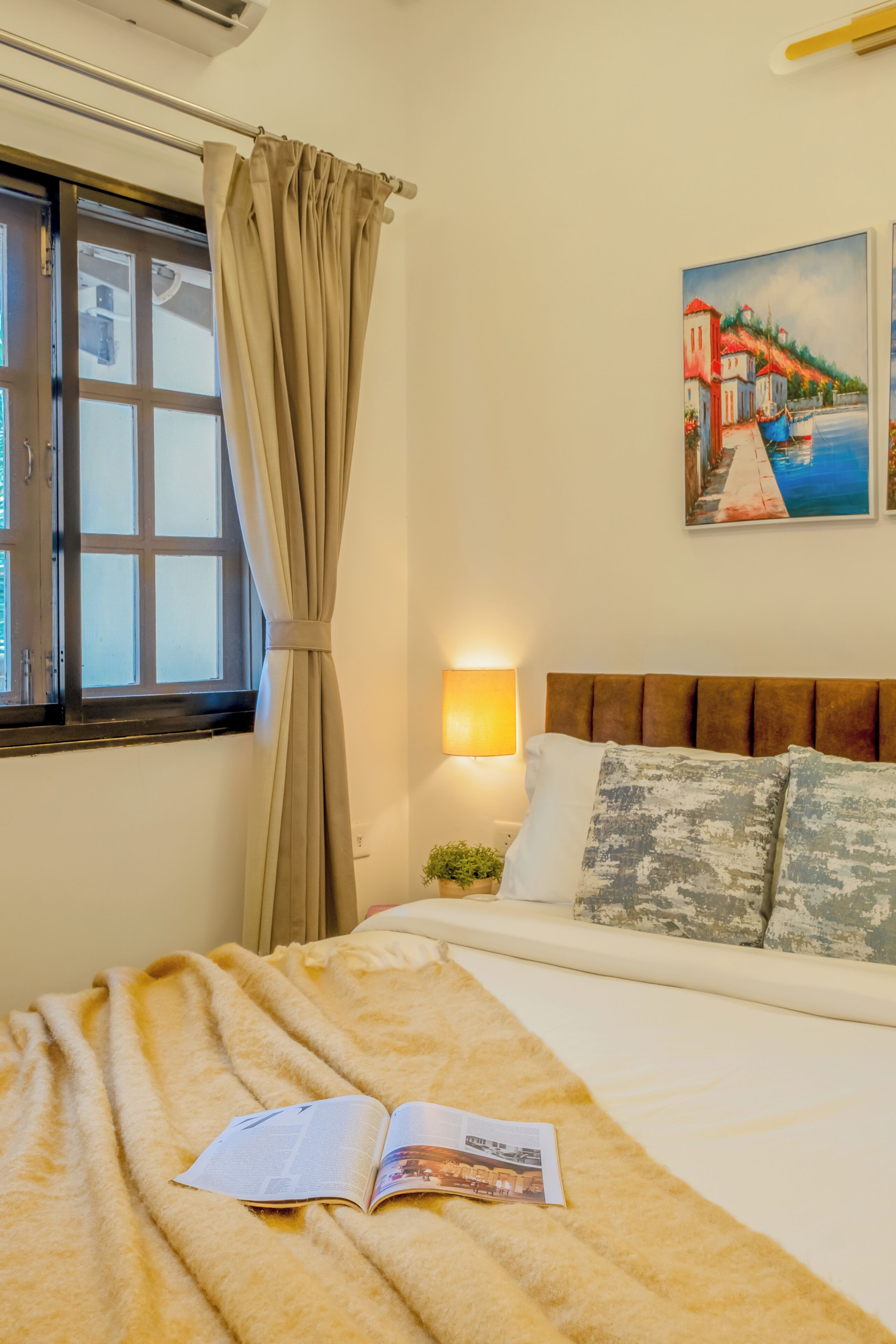 Una camera da letto con un letto, una finestra con tende, una lampada a parete e un quadro.
