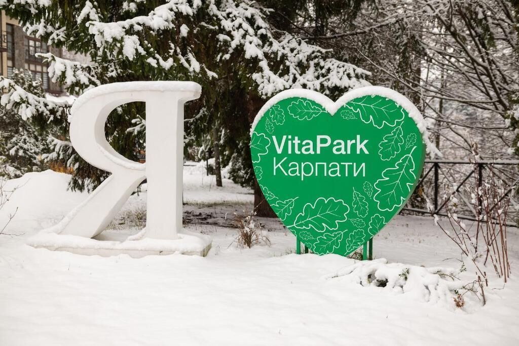 Een bord met 'VitaPark Kaplany' in een hartvorm, omgeven door sneeuw.