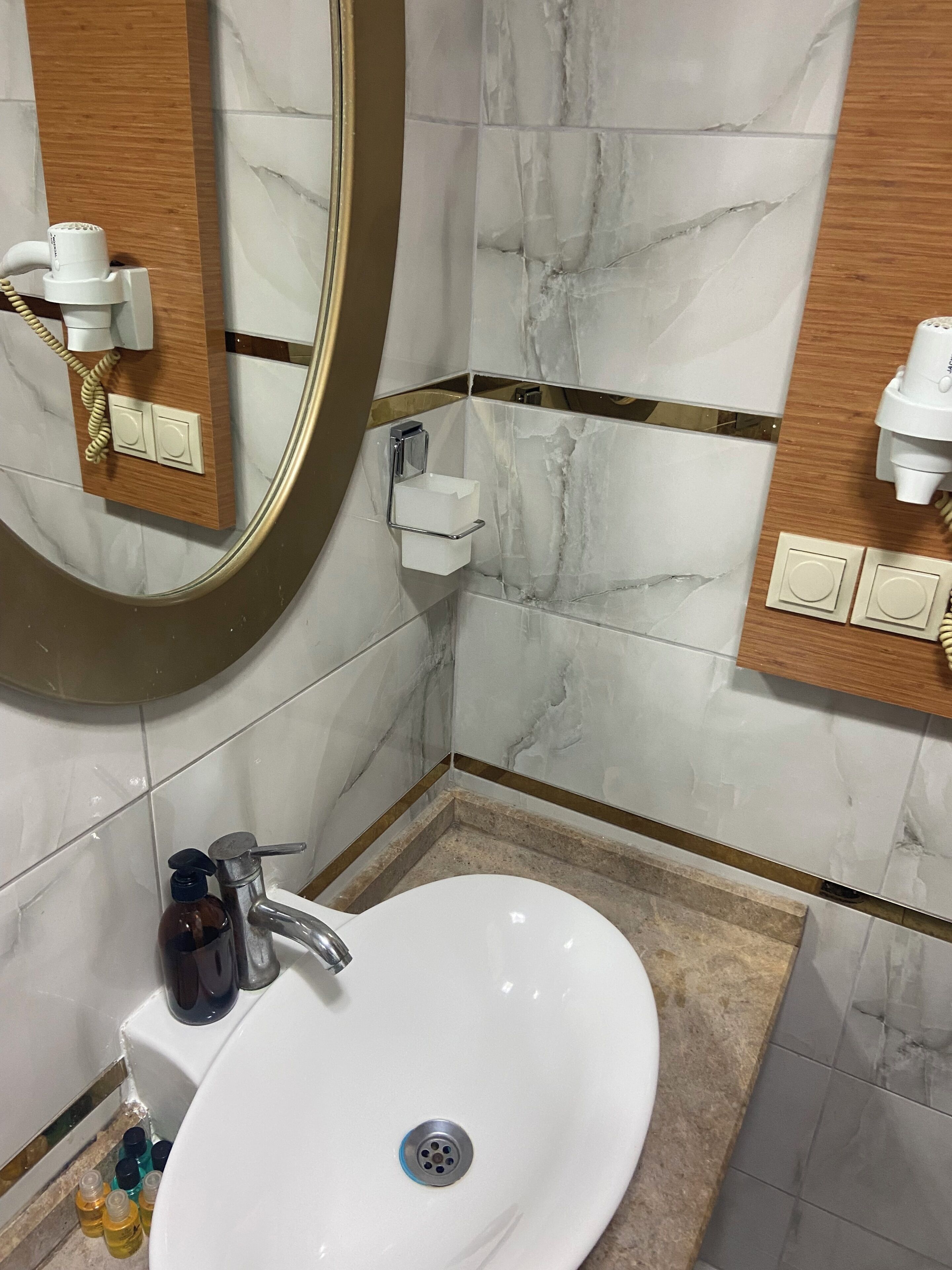 Un baño con un lavamanos blanco, un espejo, un perchero para toallas y un dispensador de jabón.