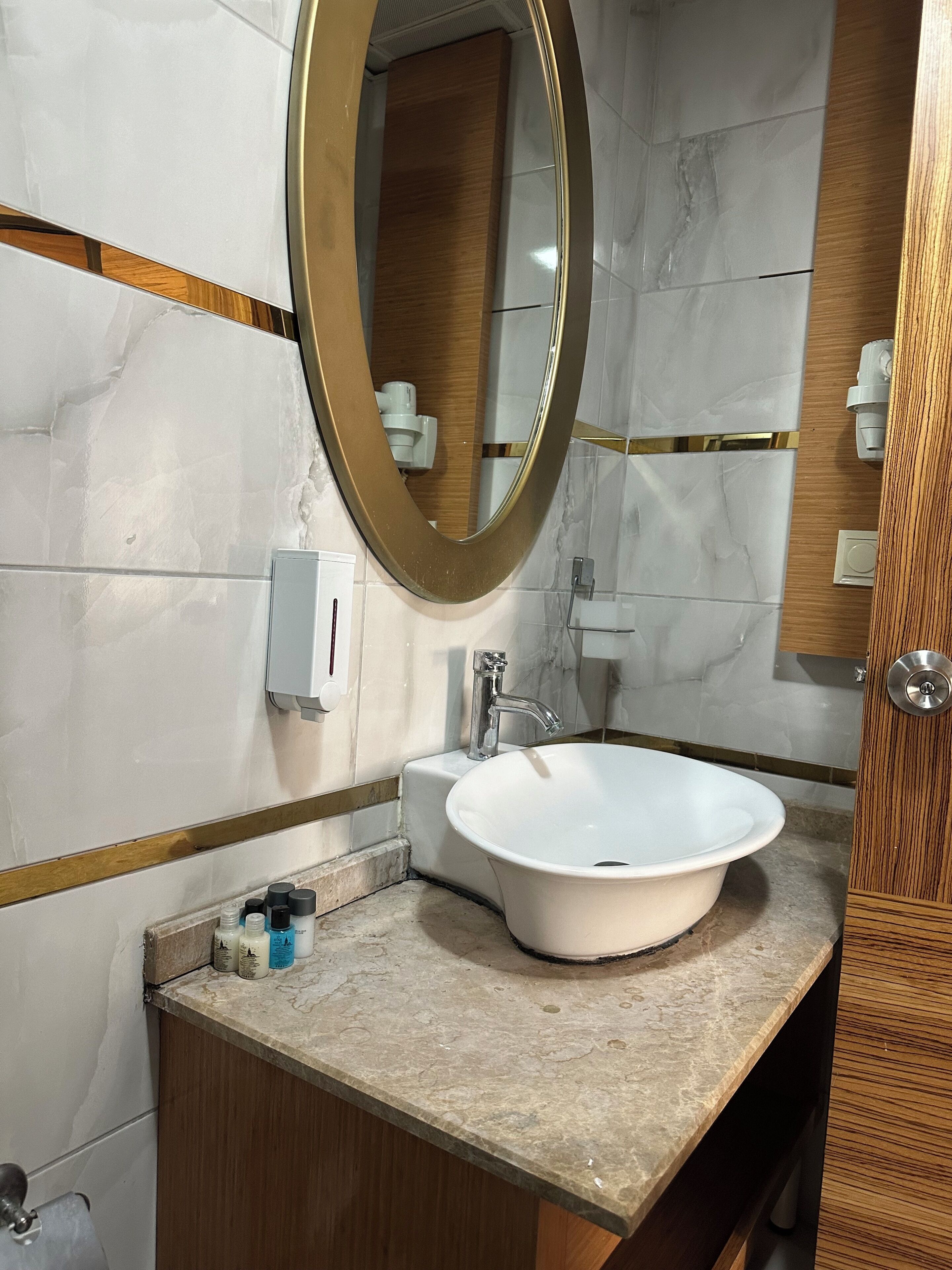 Un baño con lavamanos blanco, espejo y tocador de madera.